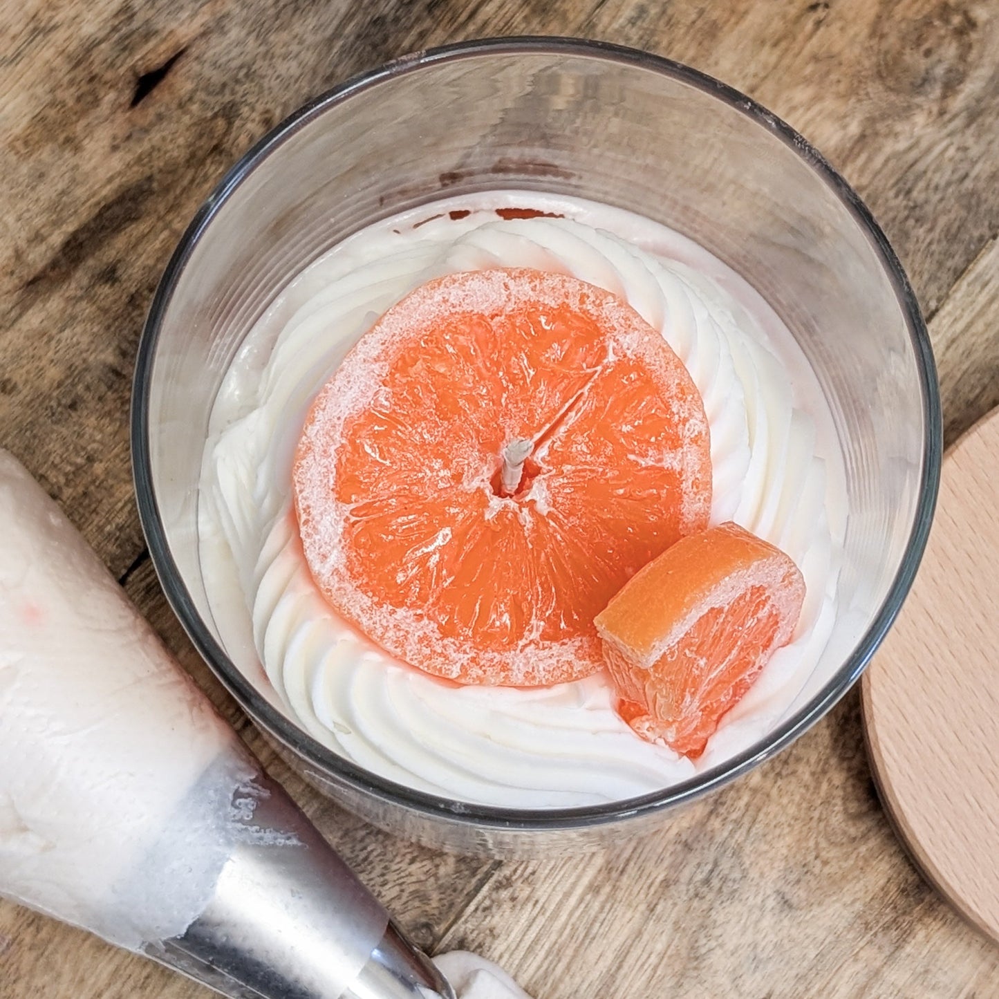 Bild zeigt die Draufsicht einer der "Dessert Inflame" Duftkerzen im Glas. Das Topping ist einer Orangenscheibe in knalligen Orange nachempfunden.