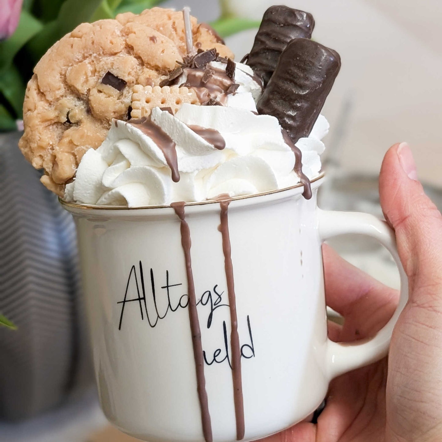Nahaufnahme einer handgemachten Dessertkerze in einer Porzellantasse, „Alltagsheld“- In der Hand gehalten zum Größenvergleich.