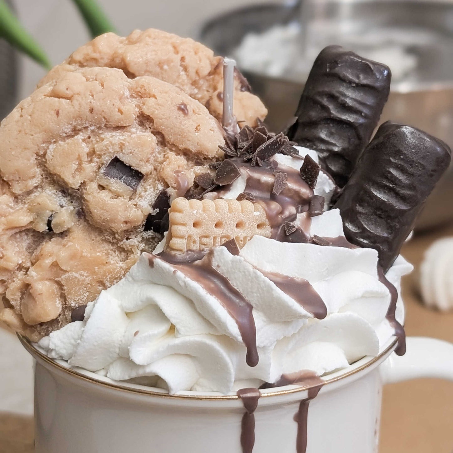 Handgemachte Dessertkerze, Detailaufnahme vom  Wachs-Topping aus Sahne, einem Cookie und zwei Schokoriegeln.